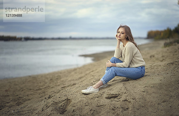 Nachdenkliche Frau am Strand sitzend