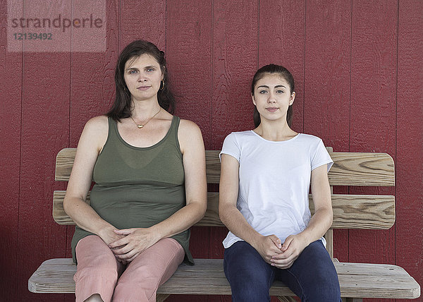 Porträt eines ernsten kaukasischen Mädchens und einer Mutter auf einer Bank