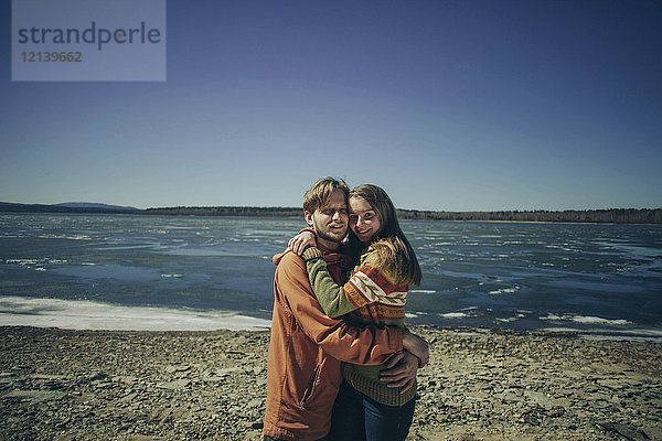 Porträt eines kaukasischen Paares  das sich am Strand umarmt