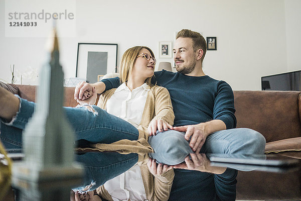 Paar auf der Couch zu Hause sitzend mit Modell des Empire State Building