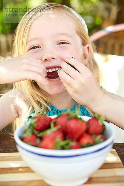 Porträt eines glücklichen Mädchens  das Erdbeeren isst.