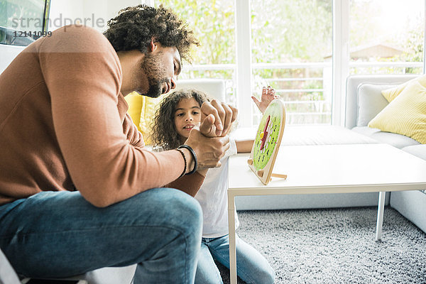 Vater hilft Tochter lernen  die Uhr zu lesen
