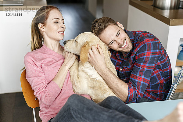 Glückliches junges Paar kuschelt mit Hund zu Hause