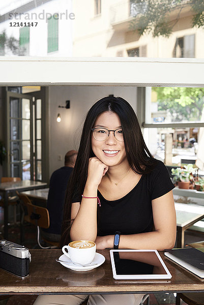 Porträt einer asiatischen jungen Frau  die in einem Coffee-Shop vor der Kamera lächelt.
