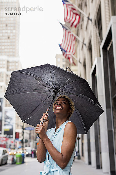 USA  New York  junge blonde Afroamerikanerin mit Regenschirm