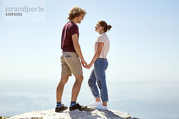 Südafrika  Kapstadt  junges Paar  das auf einem Berg an der Küste steht und Händchen hält.