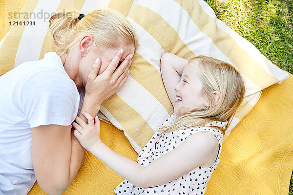 Glückliches Mädchen mit Mutter auf einer Decke liegend