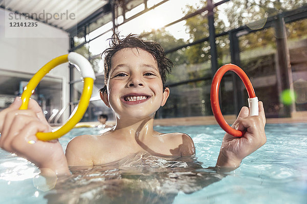 Porträt eines stolzen Jungen mit zwei Tauchringen im Schwimmbad