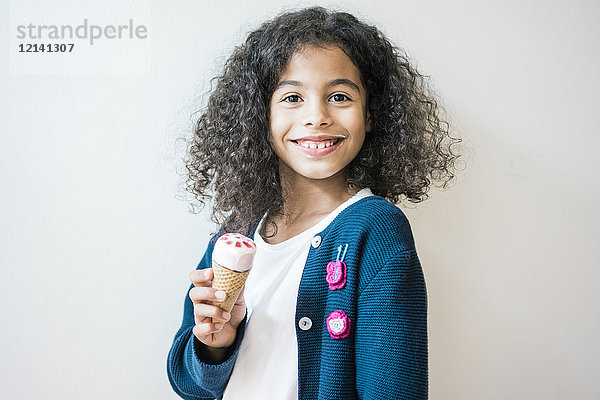 Freches kleines Mädchen lächelt in die Kamera und isst Eis.