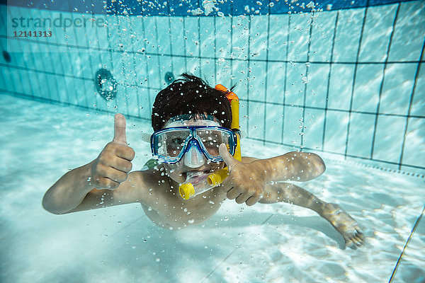 Junge mit Taucherbrille und Schnorchel unter Wasser im Schwimmbad
