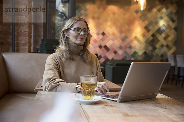 Portrait einer Geschäftsfrau bei der Arbeit am Laptop in einem Restaurant