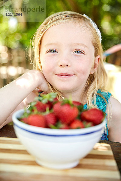 Porträt eines lächelnden Mädchens mit Schale mit Erdbeeren