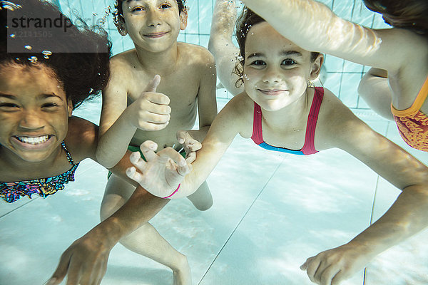 Porträt von glücklichen Kindern  die im Schwimmbad unter Wasser schwimmen.