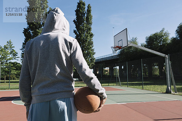 Mann hält Basketball  Reifen im Hintergrund