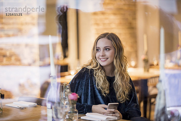 Porträt einer lächelnden jungen Frau  die in einem Restaurant wartet.