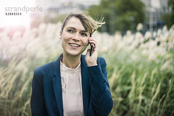 Lächelnde Geschäftsfrau am Handy im Freien