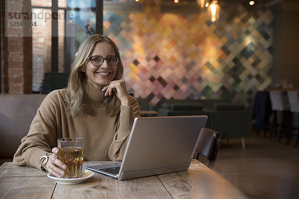 Portrait der lachenden Geschäftsfrau mit Laptop im Restaurant