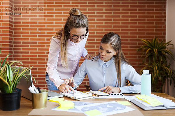 Zwei Geschäftsfrauen mit Notebook am Schreibtisch im Büro