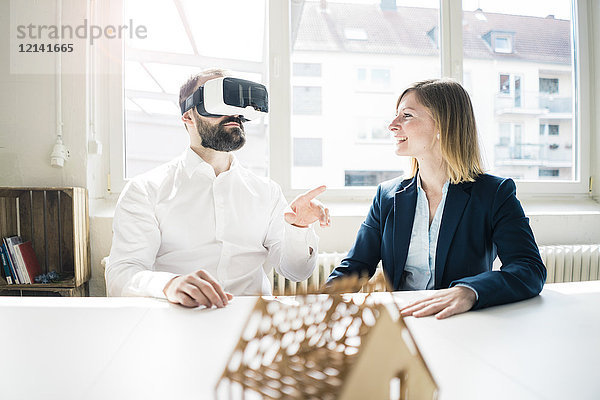 Frau und Mann mit Hausmodell und VR-Brille im Büro