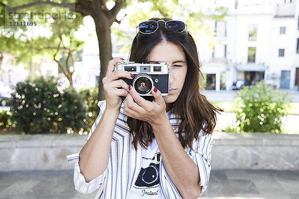 Junge Frau beim Fotografieren mit Vintage-Kamera