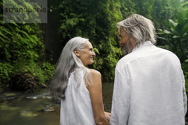 Hübsches Seniorenpaar lächelt sich im tropischen Dschungel an.