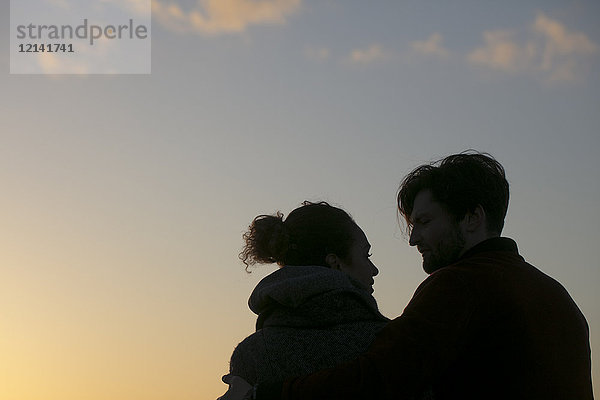 Silhouette eines jungen Paares im Freien bei Sonnenuntergang