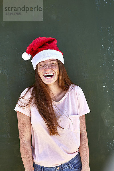 Porträt einer lachenden jungen Frau mit Weihnachtshut