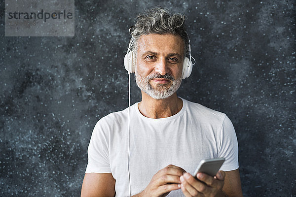 Porträt eines reifen Mannes mit Smartphone und Kopfhörern