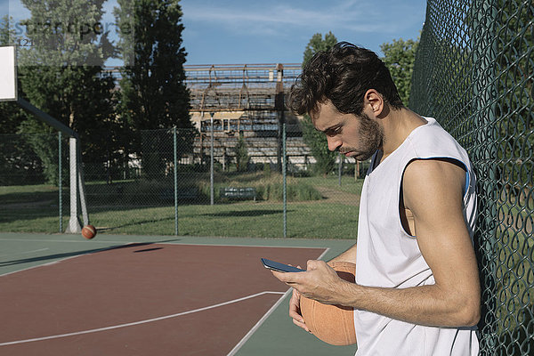 Basketballspieler beim Blick auf das Smartphone