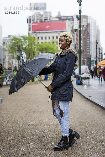 USA  New York City  Portrait einer lachenden jungen Frau mit Regenschirm