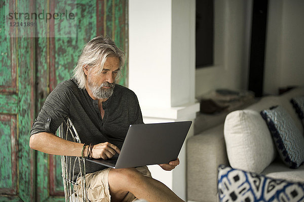 Älterer Mann bei der Arbeit am Laptop in seinem stilvollen Zuhause