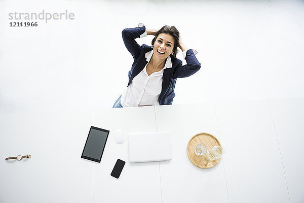 Porträt einer lachenden Geschäftsfrau bei einer Pause am Schreibtisch im Büro  Draufsicht