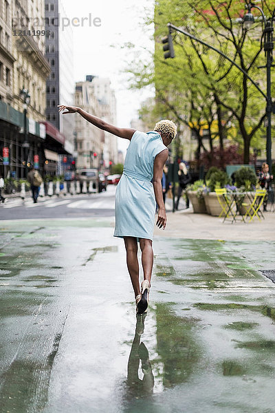 USA  New York  junge blonde Afroamerikanerin in der Pfütze wandelnd