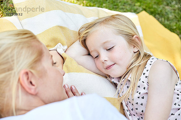 Lächelndes Mädchen und Mutter auf einer Decke liegend
