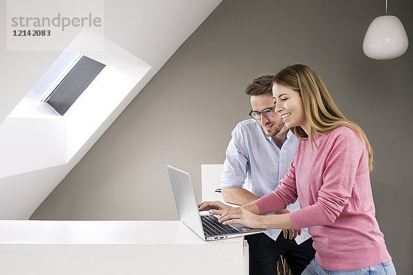 Lächelnder Mann und Frau teilen sich einen Laptop