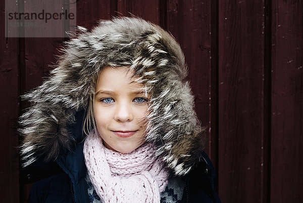 Porträt eines kleinen Mädchens mit windgepeitschter Fellkapuze