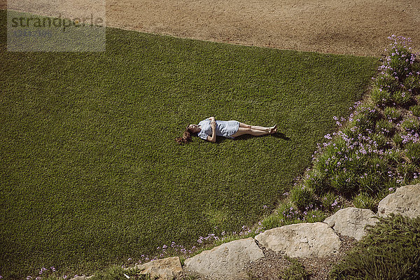 Frau auf Rasen im Garten liegend