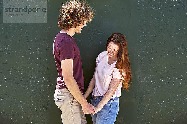 Glückliches junges Paar vor einer grünen Wand