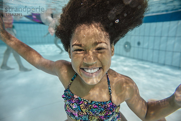 Porträt des lächelnden Mädchens unter Wasser im Schwimmbad