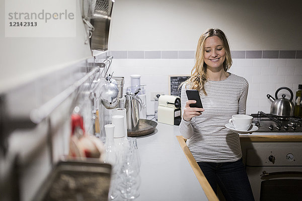Lächelnde Frau beim Telefonieren in der Küche