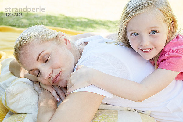 Mutter und Tochter entspannt auf einer Decke liegend