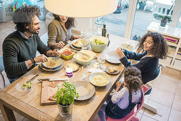 Glückliche Familie beim gemeinsamen Essen von Pizza und Pasta