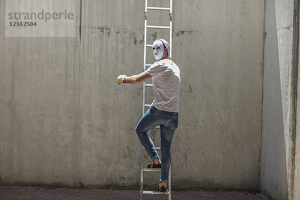 Mann mit einer Maske auf einer Leiter