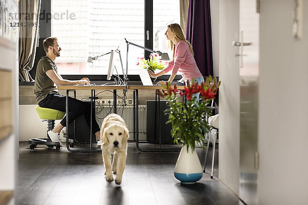 Mann und Frau mit Hund arbeiten zu Hause am Schreibtisch