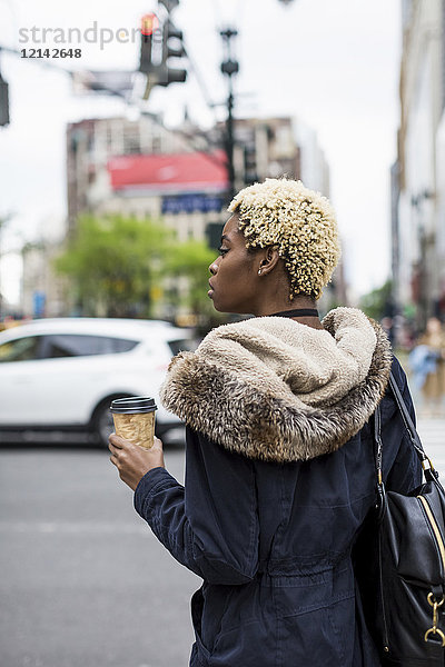 USA  New York City  modische junge Frau mit Kaffee zum Warten am Straßenrand