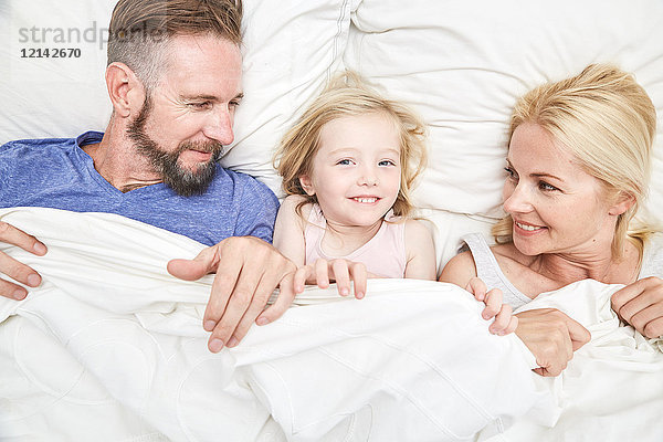 Porträt einer glücklichen Familie im Bett liegend
