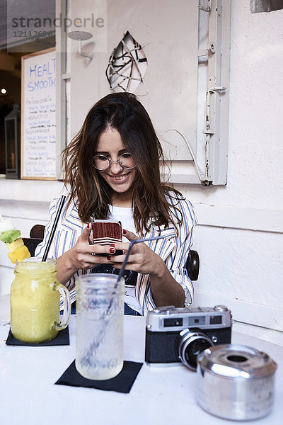 Junge Frau sitzt in einem Coffee-Shop mit Smartphone