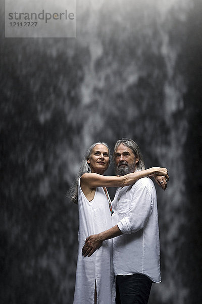 Schönes Seniorenpaar umarmt vor tropischem Wasserfall