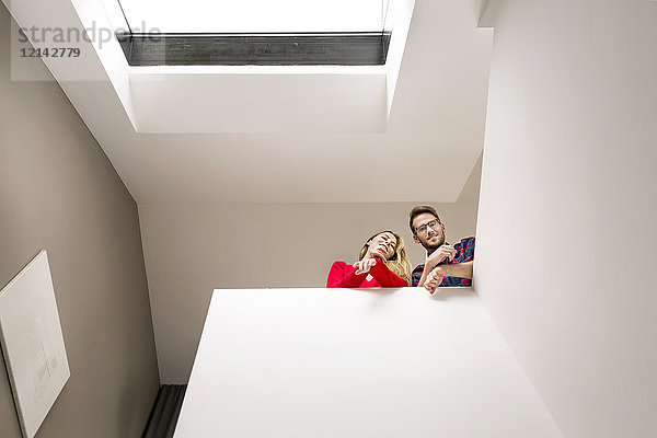Porträt eines lächelnden jungen Paares im Obergeschoss unter dem Dachfenster