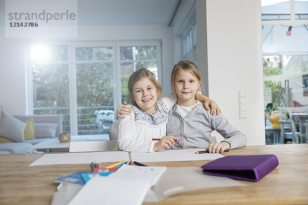 Porträt von zwei Mädchen  die gemeinsam Hausaufgaben machen.